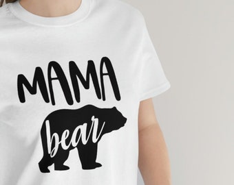 May include: White t-shirt with black text that reads "Mama bear" and a black silhouette of a bear.