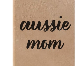 May include: A tan leather-bound journal with the text "aussie mom" printed in black cursive.