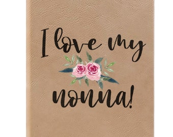 May include: A brown leather journal with the text "I love my nonna!" in black lettering. The text is surrounded by a watercolour illustration of pink roses and green leaves.