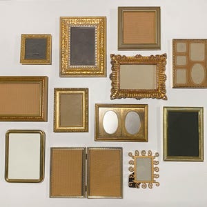 May include: A collection of twelve gold-toned picture frames in various shapes and sizes, including rectangular, square, and oval designs. The frames feature diverse textures, ranging from smooth metallic finishes to ornate, embossed, and scrollwork patterns.