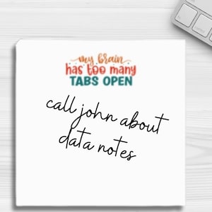May include: A white sticky note with the text "my brain has too many TABS OPEN" in red, teal, and orange. Below, handwritten text reads "call john about data notes". A keyboard is partially visible in the background.