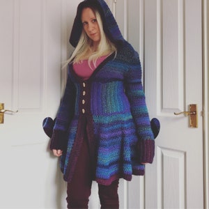 May include: A long-sleeved, crocheted cardigan with a hood. The cardigan is a mix of purple, blue, and green colors. It has a button-up front and a flared hem.