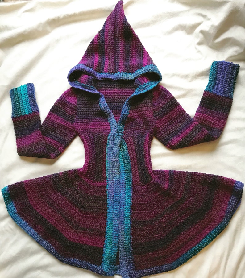 May include: A purple, blue, and green striped crocheted hooded cardigan with a long, flowing hem.
