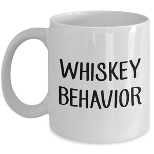 Könnte beinhalten: Weiße Keramik-Kaffeetasse mit schwarzem Text, der "Whiskey Behavior" lautet.