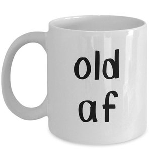 May include: White ceramic coffee mug with black text that reads "old af".