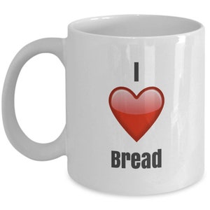Könnte beinhalten: Weiße Keramik-Kaffeetasse mit einem roten Herzen und dem Text "Ich liebe Brot".