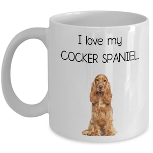May include: White ceramic mug featuring the text "I love my COCKER SPANIEL" and a brown Cocker Spaniel illustration. The mug has a curved handle and a glossy finish, ideal for dog enthusiasts.