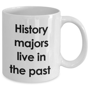 May include: White ceramic coffee mug with black text that reads "History majors live in the past".