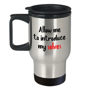 May include: A stainless steel travel mug with a black lid and handle. The mug has the text "Allow me to introduce my selves" printed on it, with the word "selves" in red.
