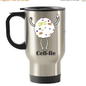 May include: Stainless steel travel mug with a black handle and lid. The mug features a cartoon cell with arms and legs holding a phone, with the text "Cell-fie" below.