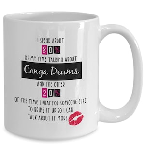 May include: White ceramic mug with a black and pink design. The mug reads "I spend about 80% of my time talking about Conga Drums and the other 20% of the time I pray for someone else to bring it up so I can talk about it more".