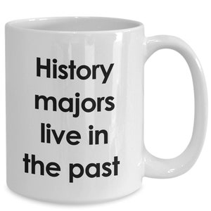 May include: White ceramic coffee mug with black text that reads "History majors live in the past".