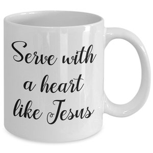 May include: White ceramic coffee mug with black text that reads "Serve with a heart like Jesus".