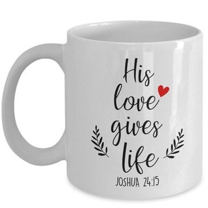 Puede incluir: Taza de café de cerámica blanca con texto negro que dice "His love gives life" con un pequeño corazón rojo y una referencia bíblica "JOSHUA 24:15".