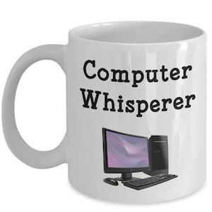 May include: White ceramic mug with a black design that says "Computer Whisperer". The design also includes a black computer monitor, a black computer tower, a black keyboard, and a black mouse.