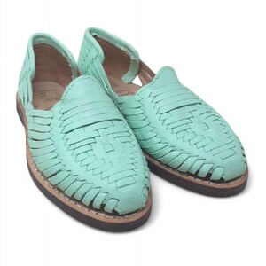 May include: A pair of mint green huarache sandals. The sandals have a woven leather design on the upper and a brown sole. The open-toe shoes are displayed on a white background. The sandals are a type of footwear.