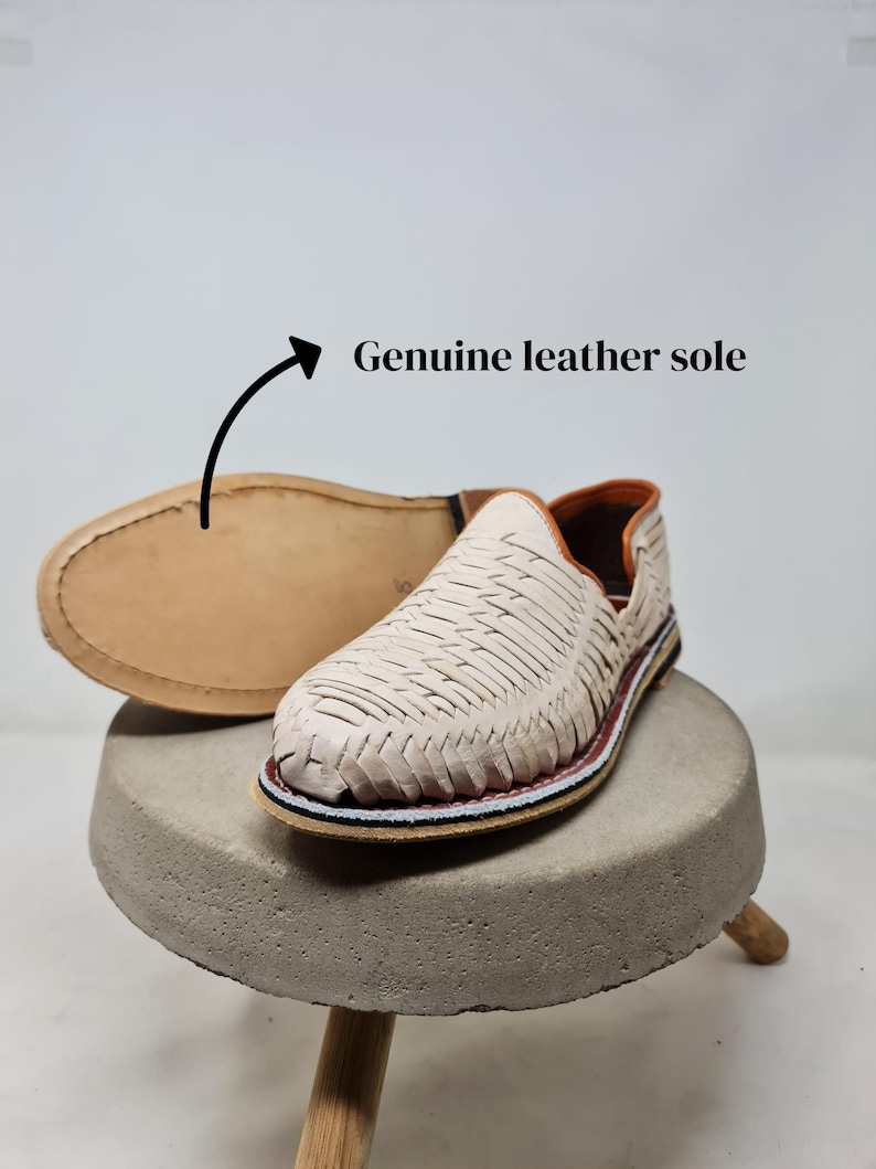 May include: A white ceramic mug with a black handle and the text "But First, Coffee" in a black, handwritten-style font. The mug is on a white surface.