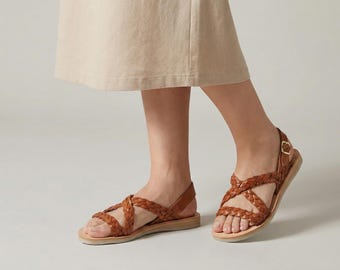 Può includere: Sandali in pelle marrone con design a cinturini intrecciati. I sandali hanno una suola piatta e una chiusura con fibbia. I sandali sono di colore marrone caldo e sembrano essere in pelle. Stile casual.