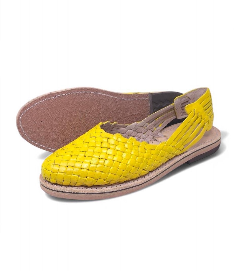 May include: Yellow leather sandals with a woven design. The sandals have a strap that goes around the ankle and a closed toe.