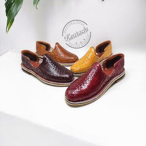 May include: Four pairs of woven leather shoes in shades of brown, burgundy, and yellow. The shoes have a slip-on design with a low heel and a textured appearance. The brand name "Kwarachi" is visible in a circular logo.
