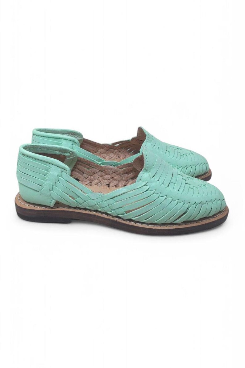 May include: A pair of mint green leather huarache sandals. The sandals have a woven design across the top and a brown sole. The open-toe shoes have a low heel and are designed for casual wear.