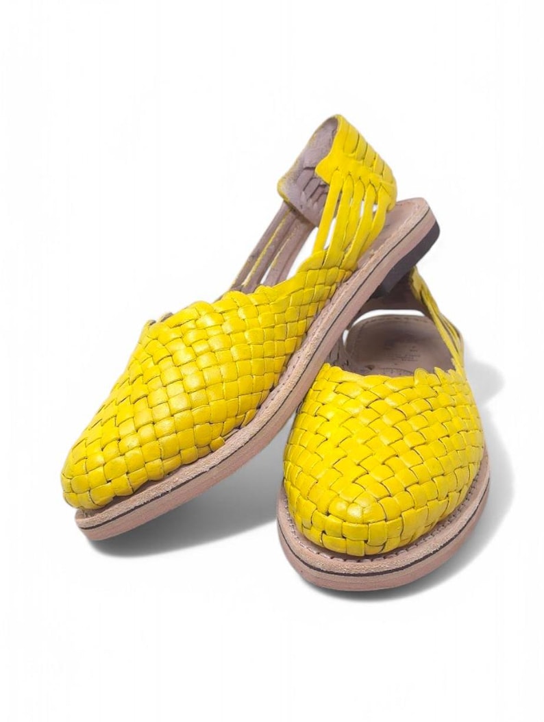 May include: A pair of yellow woven leather sandals with a closed toe and an open heel. The sandals have a simple design and are made of a soft, comfortable material.