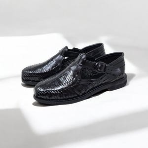 May include: A pair of black leather huarache sandals. The sandals feature a woven design across the top and a buckle closure on the side. The shoes are set against a white background.