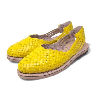 May include: A pair of yellow woven leather sandals with a simple design. The sandals have a flat sole and an open toe.