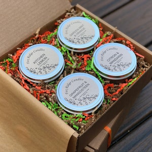 May include: A gift box filled with four small, silver candle tins. Each tin has a label with a different fruit scent: Kitchen Lemon, Garden Mint & Orange, Grapefruit & Mangosteen, and Citron & Mandarin.