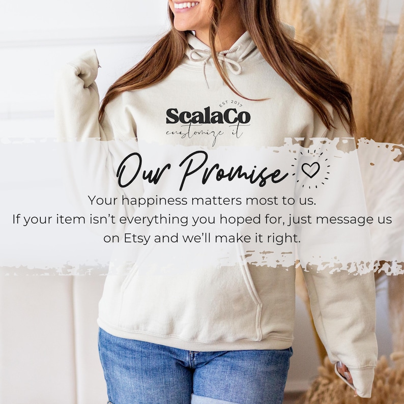 A woman wearing a white hoodie with text on it, smiling and gesturing with her hand.