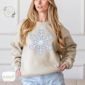 a woman wearing a sweater with a snowflake on it