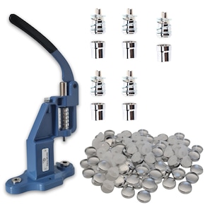 May include: A blue button press machine with a black handle, silver components, and a pile of silver button backs. Also included are several silver button press components.
