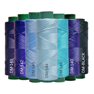 May include: A collection of spools of thread in various shades of blue, teal, and black. Each spool is labeled with a DM code. The colors range from light blue to deep indigo, with a black spool at the end. The spools have green bases.