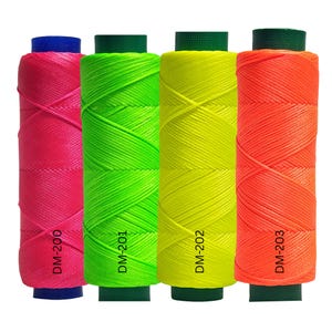 May include: Four spools of brightly colored thread: hot pink, neon green, yellow, and orange. Each spool has a different color base and is labeled with a DM number. The thread is tightly wound, showing the texture of the material.