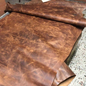 May include: A large piece of brown leather with a mottled, distressed look. The leather is folded in half and appears to be very soft and supple.