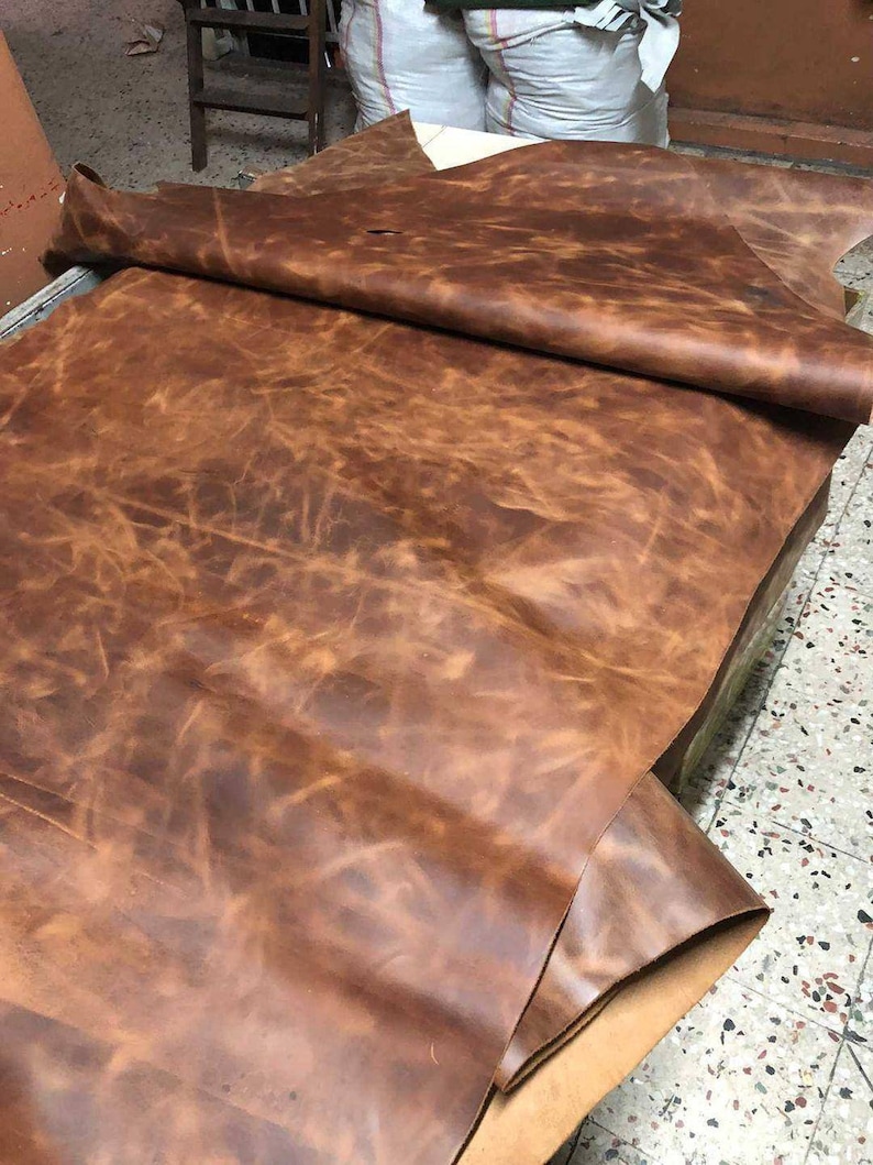 May include: A large piece of brown leather with a mottled, distressed look. The leather is folded in half and appears to be very soft and supple.