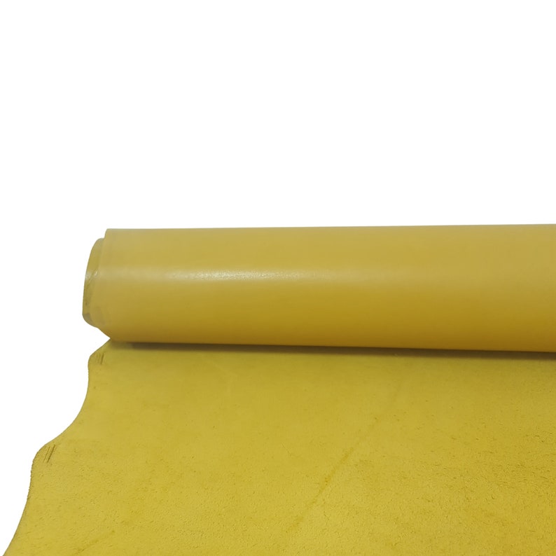 Puede incluir: Un rollo de tela de cuero amarillo. El cuero es liso y tiene un ligero brillo.