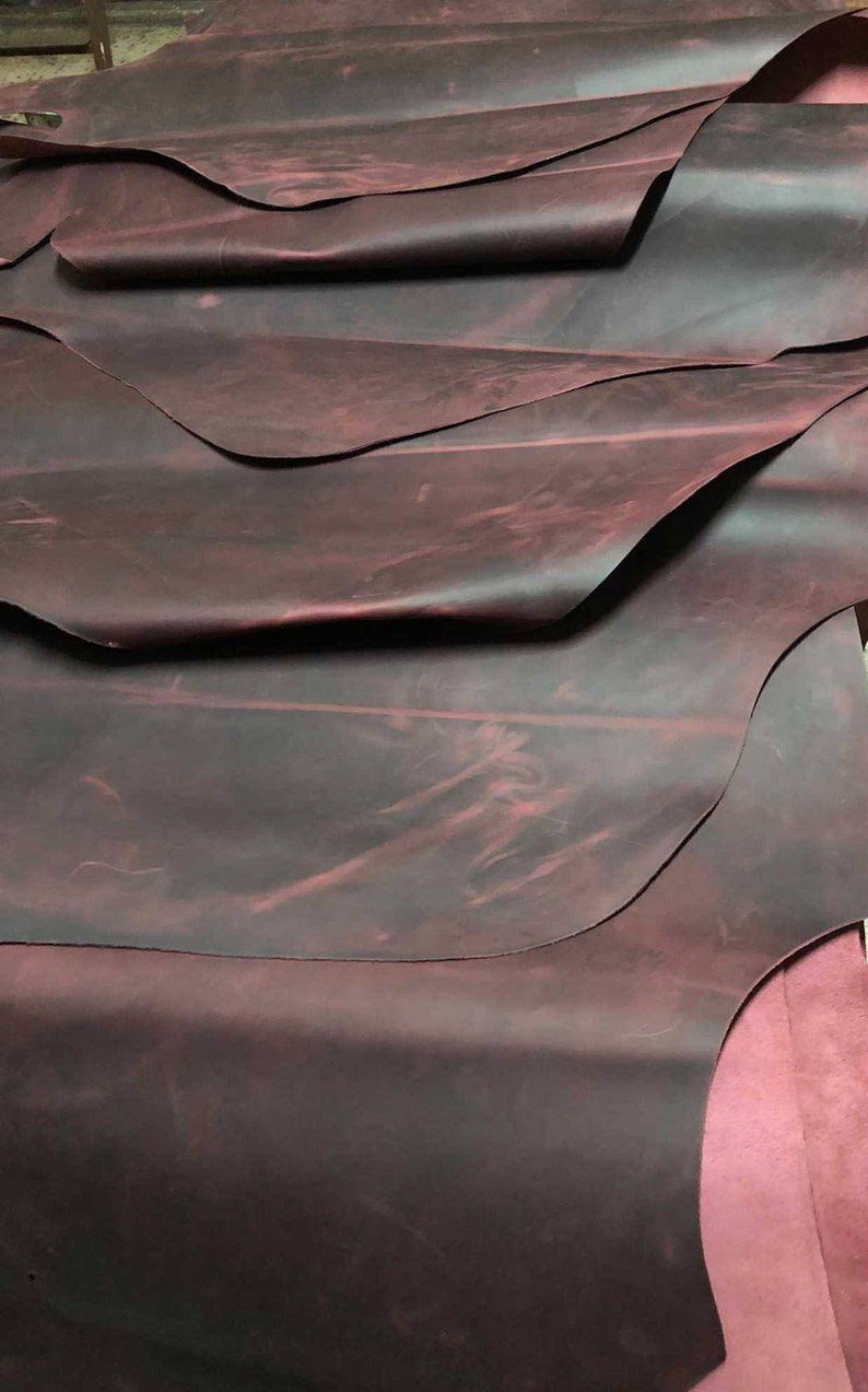 May include: A stack of dark red leather hides with a mottled, distressed finish.