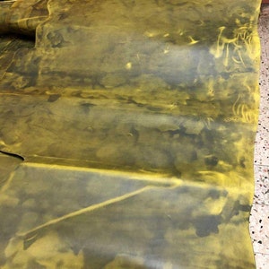 May include: A large piece of yellow leather with dark green and brown markings. The leather is folded in several places.