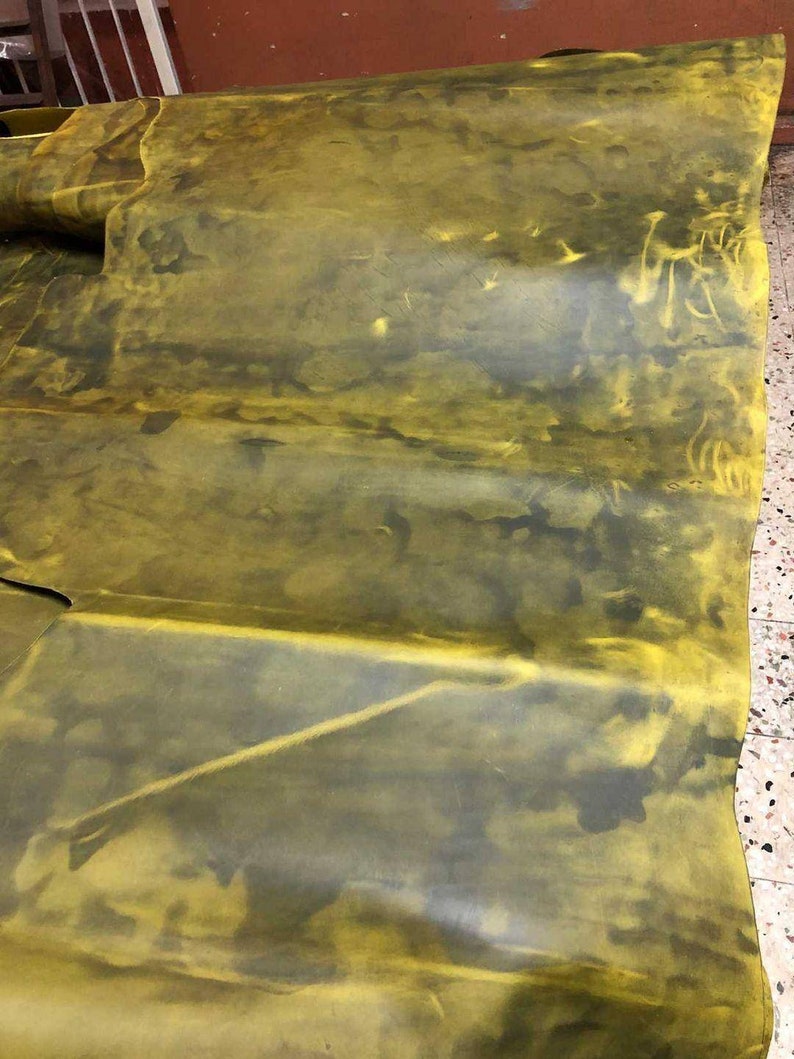 May include: A large piece of yellow leather with dark green and brown markings. The leather is folded in several places.