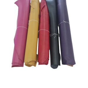 Puede incluir: Cinco rollos de cuero en diferentes colores: rosa, amarillo, rojo, negro y morado. El cuero est&aacute; enrollado y atado con una cuerda.