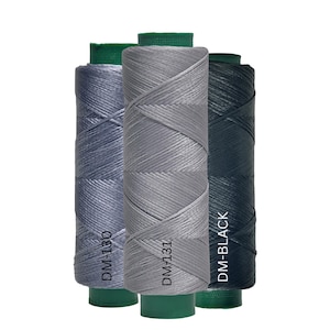 May include: Three spools of waxed thread in shades of gray and black. The spools are labeled DM-130, DM-131, and DM-BLACK. Each spool has a green base.