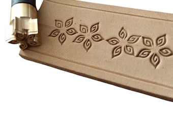 May include: A brass leather stamping tool with a floral design. The tool is used to create decorative patterns on leather.