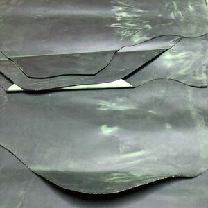 May include: A stack of dark green leather hides with a subtle green marbling effect.