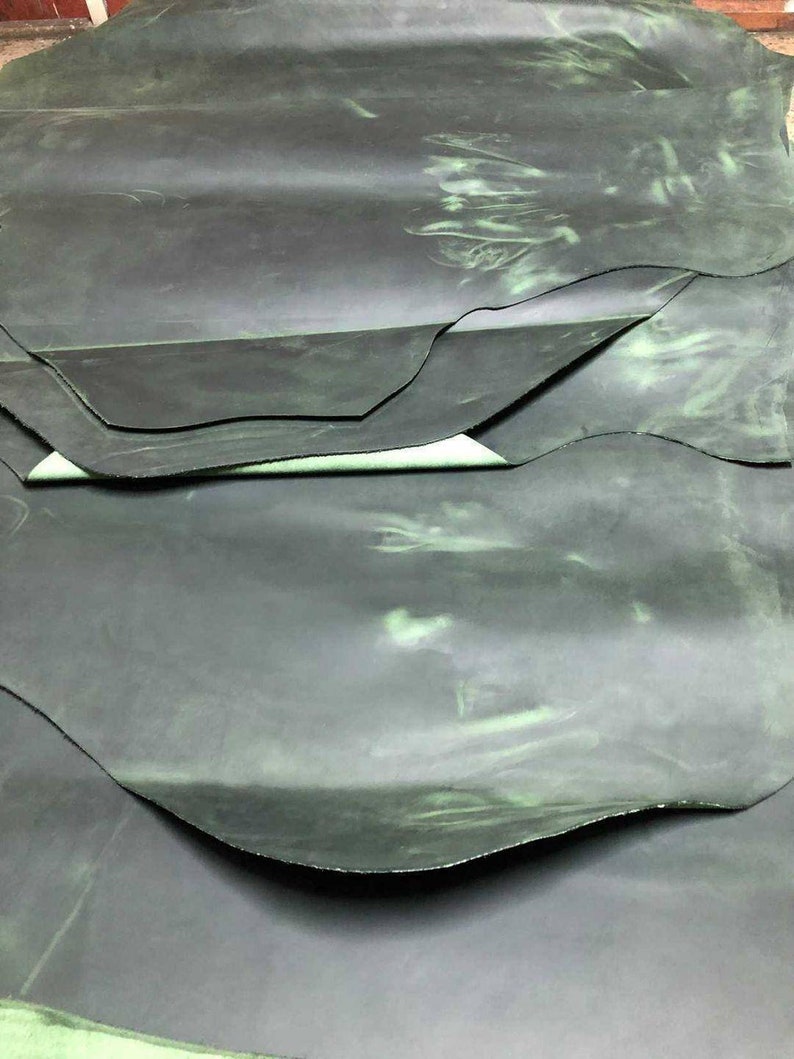 May include: A stack of dark green leather hides with a subtle green marbling effect.