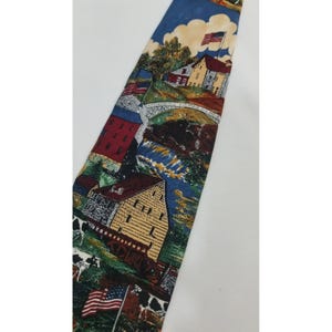 May include: A blue necktie featuring a scenic design with American flags, buildings, a bridge, and cows. The tie has a repeating pattern of a rural landscape with a blue sky and clouds.