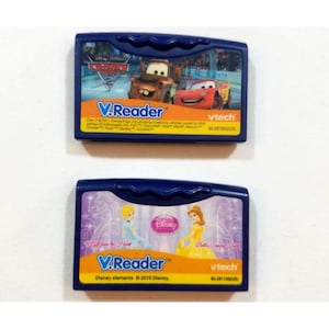 May include: Two V.Reader cartridges. One features characters from the movie "Cars" with the text "V.Reader" and "vtech". The other features Disney princesses with the text "V.Reader" and "Disney".