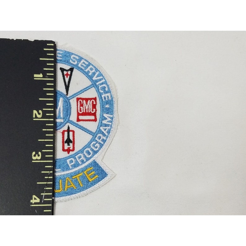 Pode incluir: Um remendo bordado azul e branco com o texto "Graduate Service Program" e um c&iacute;rculo contendo as letras "GMC" e uma estrela vermelha.