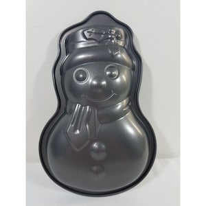 Könnte beinhalten: Eine dunkelgraue Backform in Form eines Schneemanns. Die Form zeigt ein lächelndes Schneemann-Gesicht mit Hut, Schal und Knöpfen. Die Form ist aus Metall und zum Backen von Kuchen oder anderen Leckereien in festlicher Form gedacht.