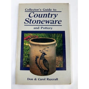 May include: A book titled "Collector's Guide to Country Stoneware and Pottery" with a blue border and a picture of a stoneware pot with a bird design. The author's names, Don & Carol Raycraft, are printed at the bottom.